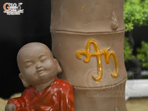 Chậu tượng trồng cây chú Tiểu áo đỏ bên gốc trúc, cao 25cm