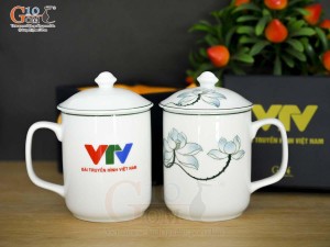 Cốc sứ có nắp men trắng vẽ sen xanh in logo VTV, đường kính 8cm