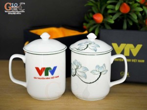 Cốc sứ có nắp men trắng vẽ sen xanh in logo VTV, đường kính 8cm
