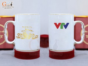 Cốc sứ dáng cao quai nắm men trắng cảnh Mã Đáo Thành Công vàng kim, in logo VTV, 450ml