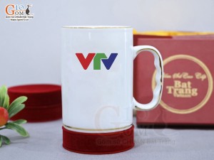 Cốc sứ dáng cao quai nắm men trắng cảnh Thuận Buồm Xuôi Gió vàng kim, in logo VTV, 450ml
