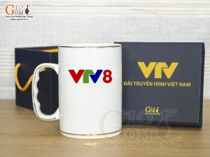 Cốc sứ dáng cao quai nắm men trắng kẻ chỉ vàng kim, in logo VTV8 450ml