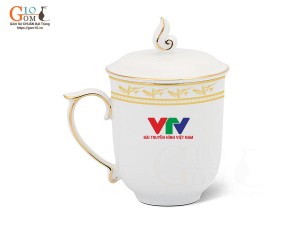 Cốc sứ dáng chóp lửa men trắng họa tiết Trống Đồng kẻ chỉ vàng kim, in logo VTV, 400ml