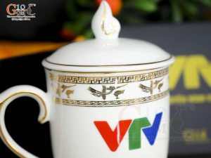 Cốc sứ dáng chóp lửa men trắng họa tiết Trống Đồng vàng kim, in logo VTV 400ml