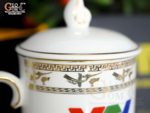 Cốc sứ dáng chóp lửa men trắng họa tiết Trống Đồng vàng kim, in logo VTV 400ml