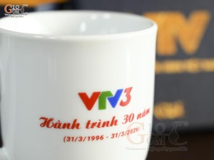 Cốc sứ dáng chóp lửa men trắng in logo Hành Trình 30 năm VTV3