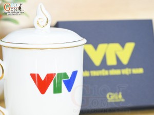 Cốc sứ dáng chóp lửa men trắng kẻ chỉ vàng kim có nắp in logo VTV, 400ml