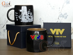 Cốc sứ dáng lục giác quai tròn màu đen cảnh Thuận Buồm Xuôi Gió, in logo VTV8
