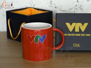 Cốc sứ dáng lục giác quai tròn màu đỏ cảnh Mã Đáo Thành Công, in logo VTV