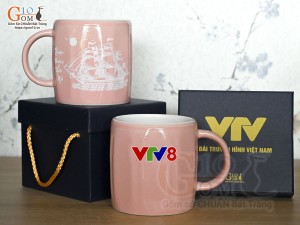 Cốc sứ dáng lục giác quai tròn màu hồng cảnh Thuận Buồm Xuôi Gió, in logo VTV8