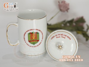 Cốc sứ dáng cao quai nắm men trắng kẻ chỉ vàng kim in logo CA TP HCM, 500ml